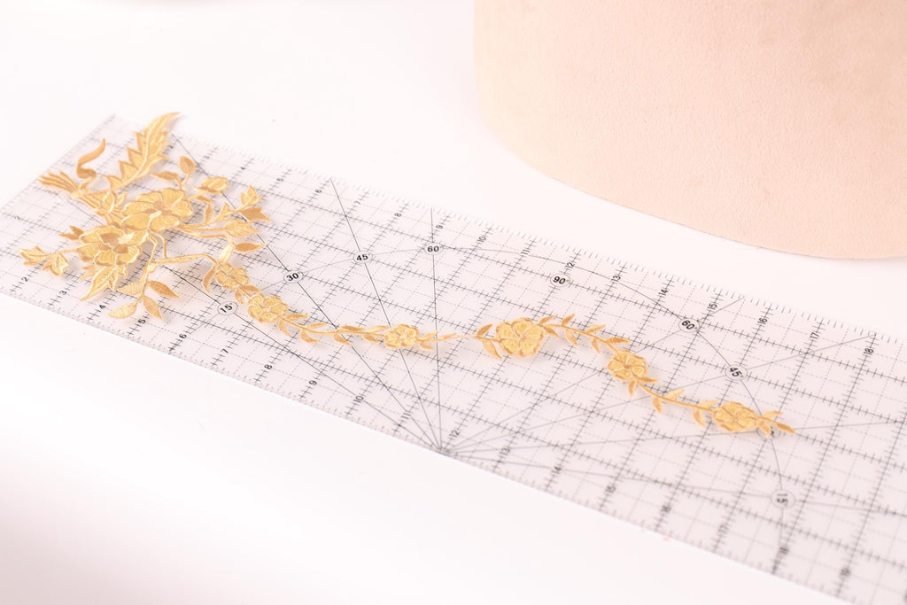 a clear ruler with a decorative gold floral pattern on it, placed on a white surface.