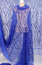 a mannequin wearing a long, flowing blue sequin dress with a sheer overlay. The dress has a pattern of blue sequins and a sheer overlay, creating a striking and elegant appearance.