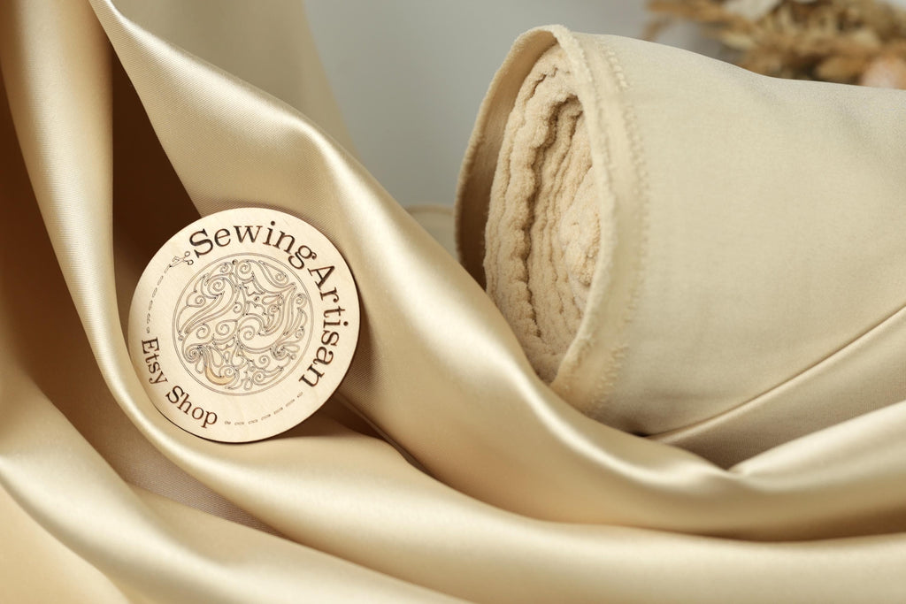 A circular wooden label with text and a design, placed on a beige fabric surface.