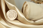 A circular wooden label with text and a design, placed on a beige fabric surface.