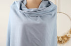 A light blue fabric draped over a mannequin, with a wreath visible in the background.