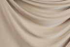a close-up view of a beige fabric, possibly a sheer or sheer-like material, with a smooth and flowing texture.