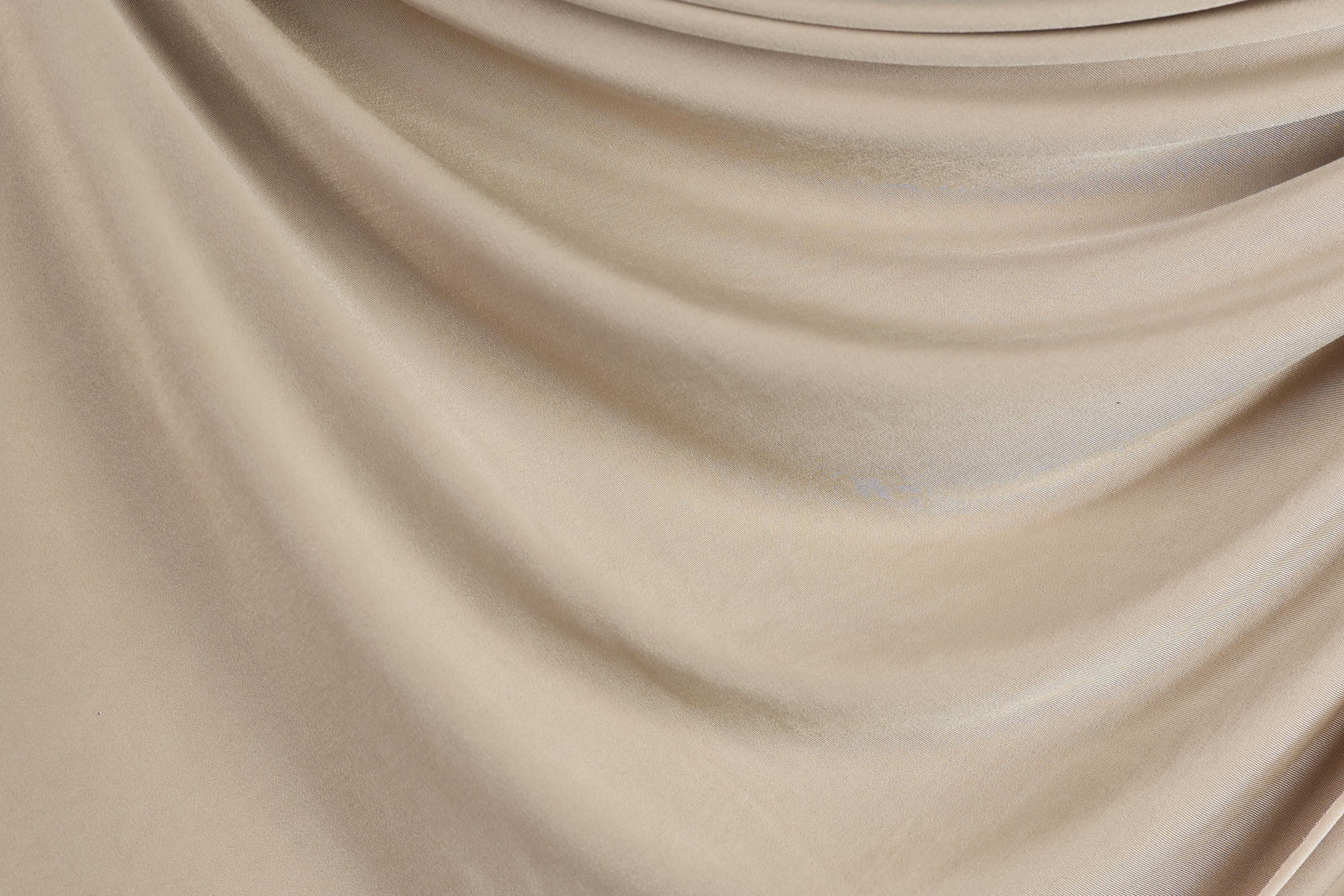 a close-up view of a beige fabric, possibly a sheer or sheer-like material, with a smooth and flowing texture.