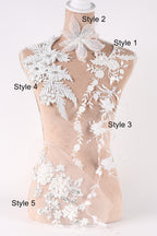 A mannequin with various white lace and floral embroidery pieces attached to it, each with a different style number.