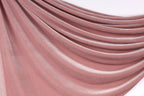 a close-up view of a soft, pink velvet fabric. The fabric has a smooth, flowing texture and is draped in a way that creates a sense of depth and movement. The color of the fabric is a rich, deep pink, which adds a sense of warmth and elegance to the image.