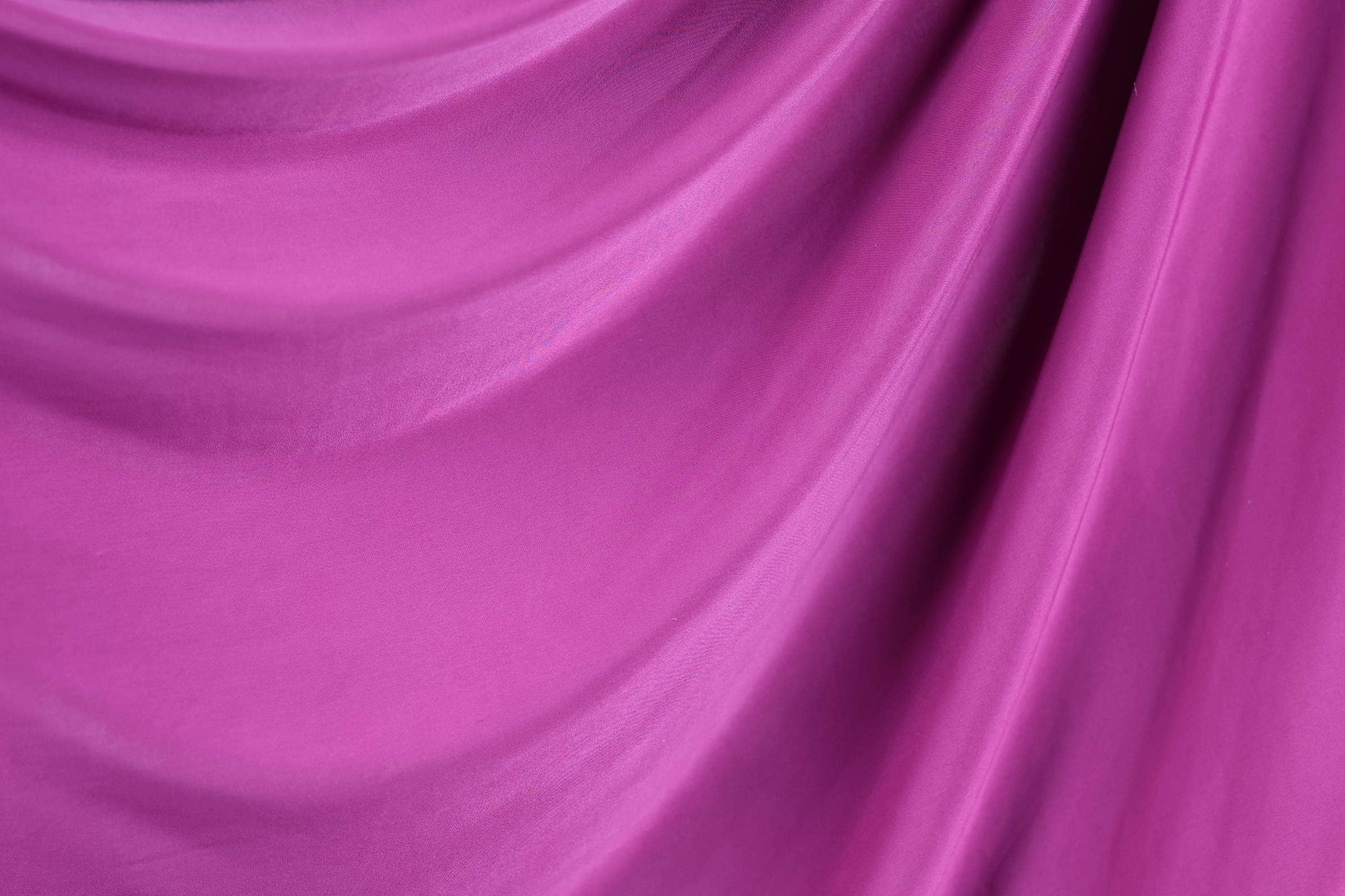 a close-up view of a vibrant, flowing purple fabric, with its texture and color creating a sense of depth and movement.