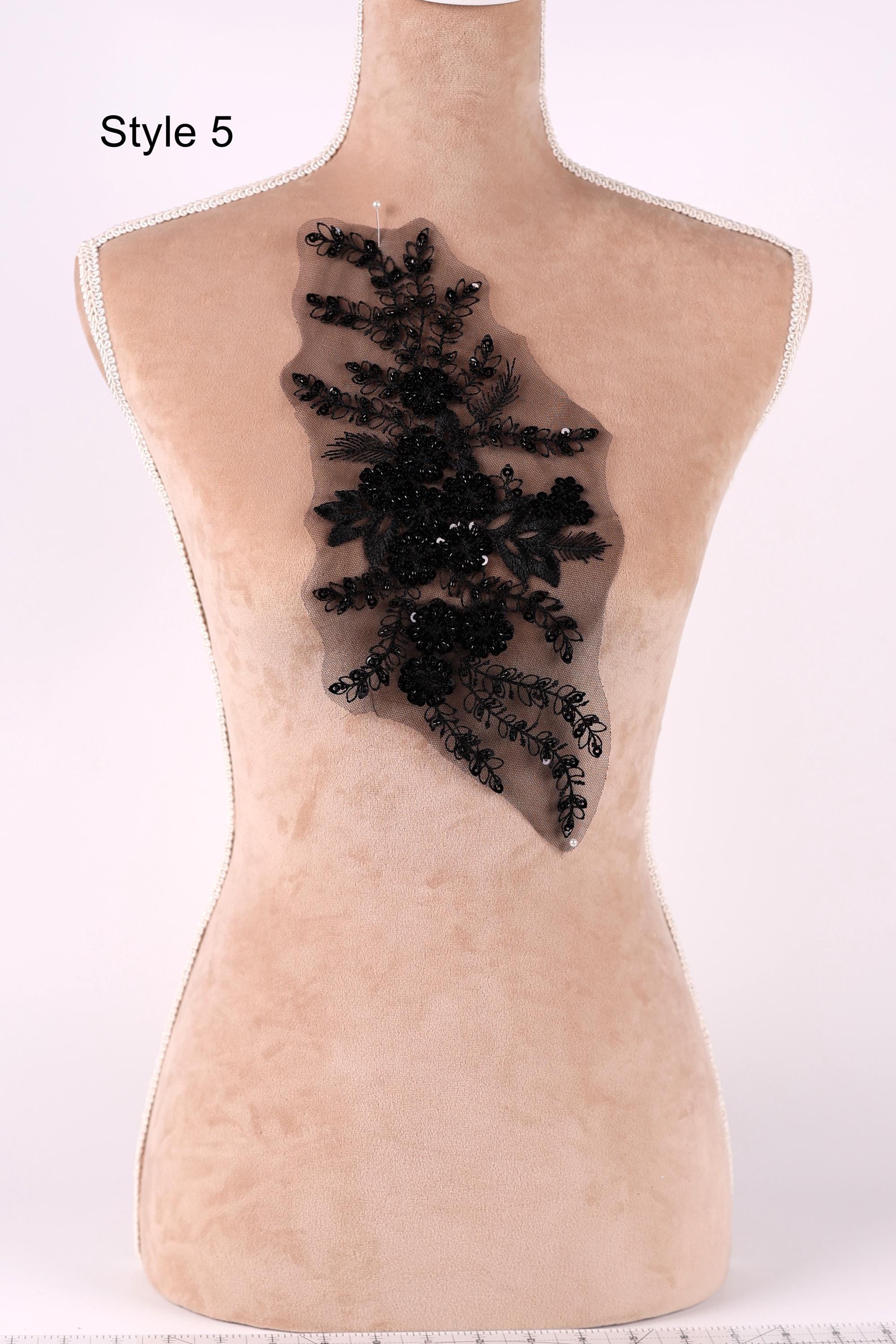 A mannequin with a decorative black lace piece on its back.
