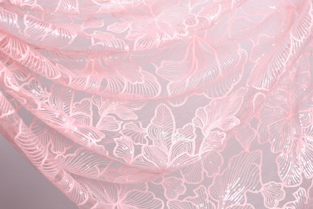 a close-up view of a delicate, pink lace fabric with a floral pattern. The lace appears to be made of a soft, delicate material and has a delicate, intricate design.