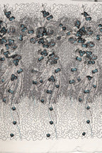 The image is a close-up of a fabric with a floral pattern, featuring a repeating design of blue flowers and leaves. The fabric appears to be made of a material with a textured surface, and the pattern is intricate and detailed.