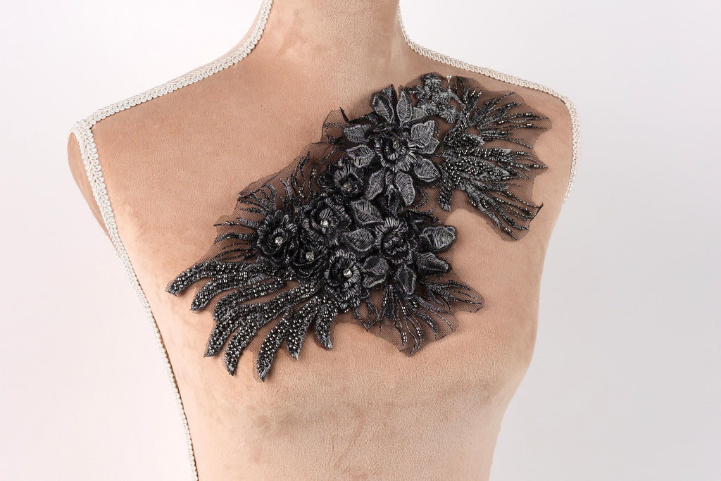 A mannequin torso with a decorative black floral embellishment on the left side.