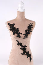 A mannequin with a beige body and black lace or floral embroidery on its torso.