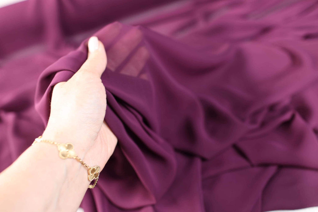 a woman's hand holding onto a purple dress