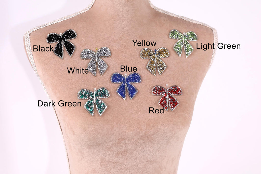 A mannequin torso with seven different colored and patterned rhinestone or crystal-like embellishments attached to it, each labeled with a color and pattern.