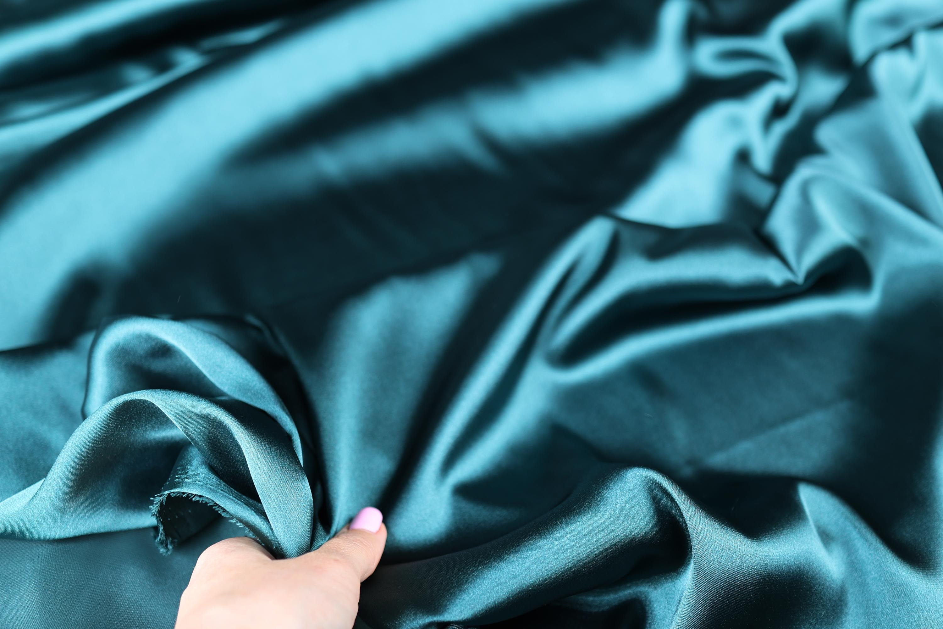 a woman&#39;s hand on a satin material