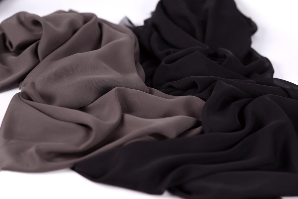 a close-up view of a crumpled fabric with a mix of dark and light colors, including shades of brown, black, and gray.