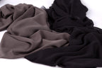 a close-up view of a crumpled fabric with a mix of dark and light colors, including shades of brown, black, and gray.