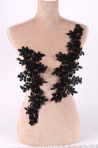 A mannequin torso with black lace appliques on it, featuring intricate floral and leaf designs.