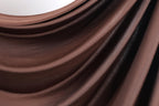 a close-up view of a brown, shiny fabric, possibly a piece of clothing or a textile. The fabric has a smooth, flowing texture and appears to be made of a shiny material, giving it a luxurious and elegant appearance.