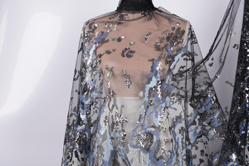 a close-up view of a sheer, black and blue sequined fabric draped over a mannequin.