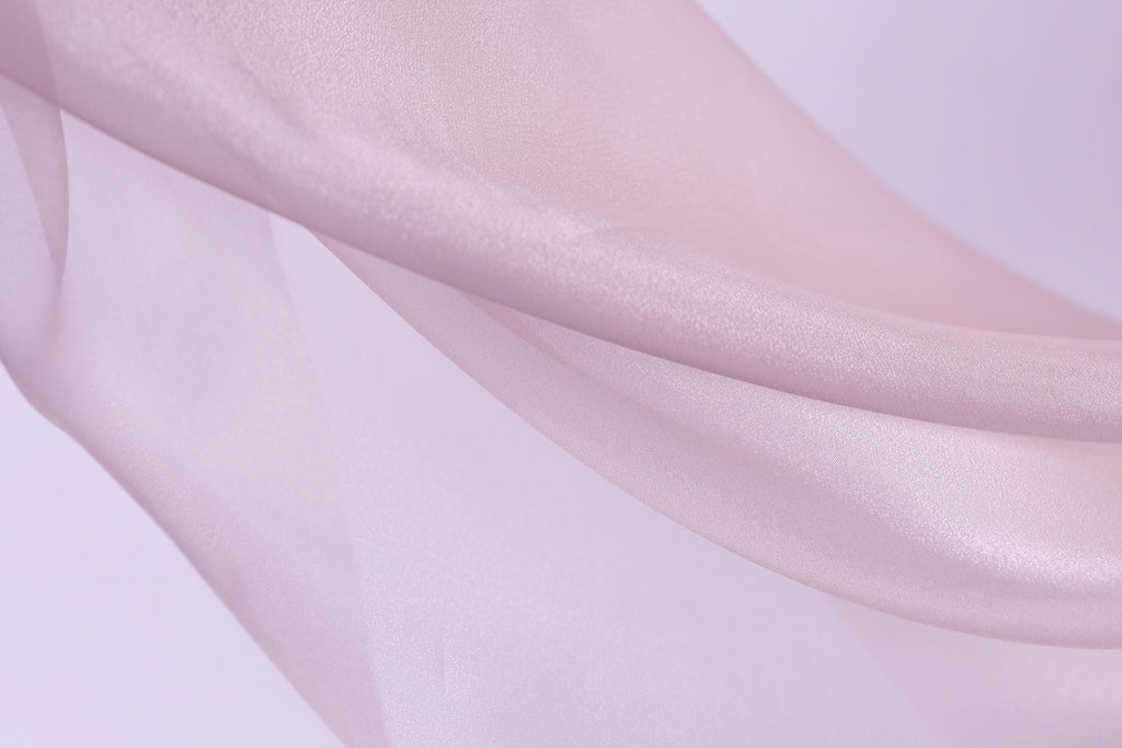 The image is a close-up of a soft, flowing fabric in a light pink color.