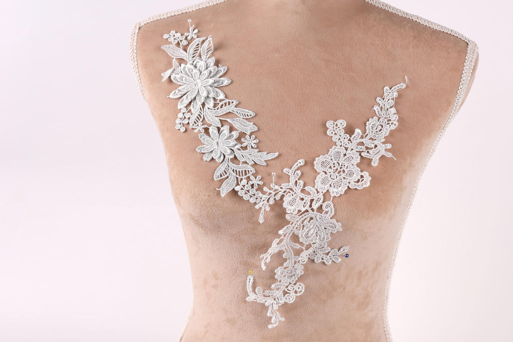 A mannequin torso with a delicate, intricate white lace design on the bust area.