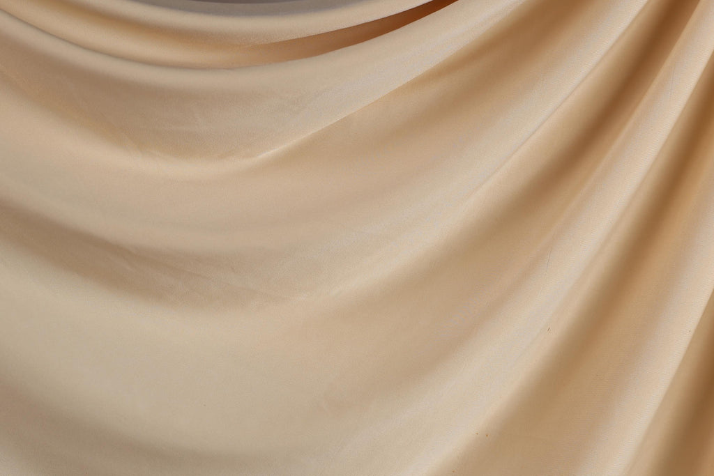 The image is a close-up of a light brown fabric, possibly a piece of clothing or a textile. The fabric appears to be soft and smooth, with a slightly wrinkled texture. The image does not contain any discernible objects or actions, and there are no specific details provided about the color or pattern of the fabric.