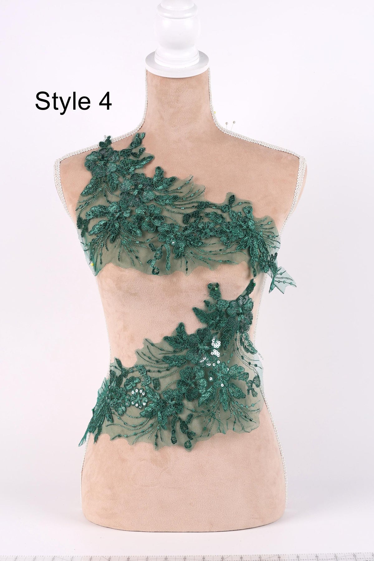 A mannequin wearing a dress with a green floral and sequin design.