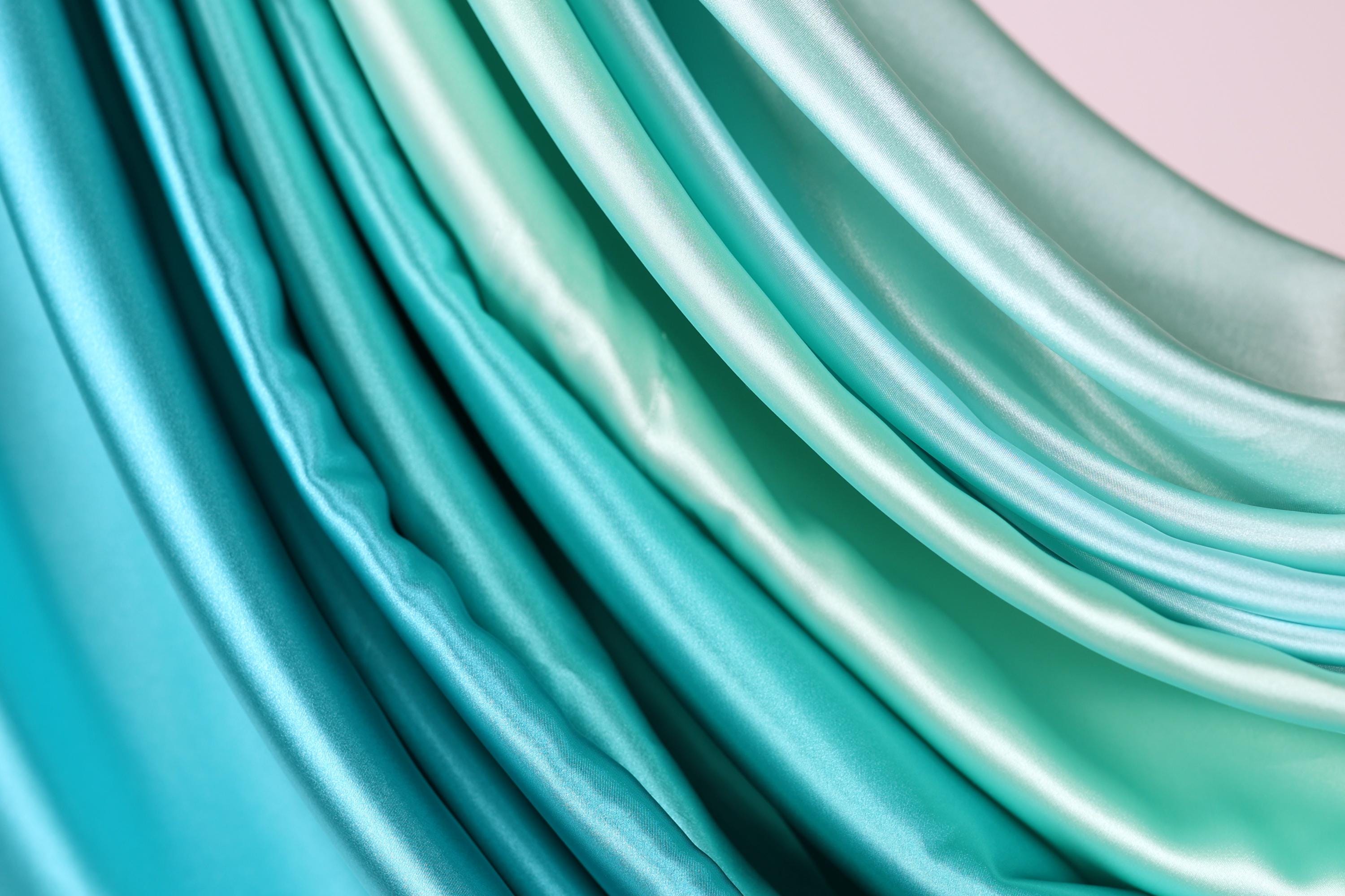A close-up view of a fabric with a gradient of turquoise and mint colors, creating a visually appealing and textured appearance.