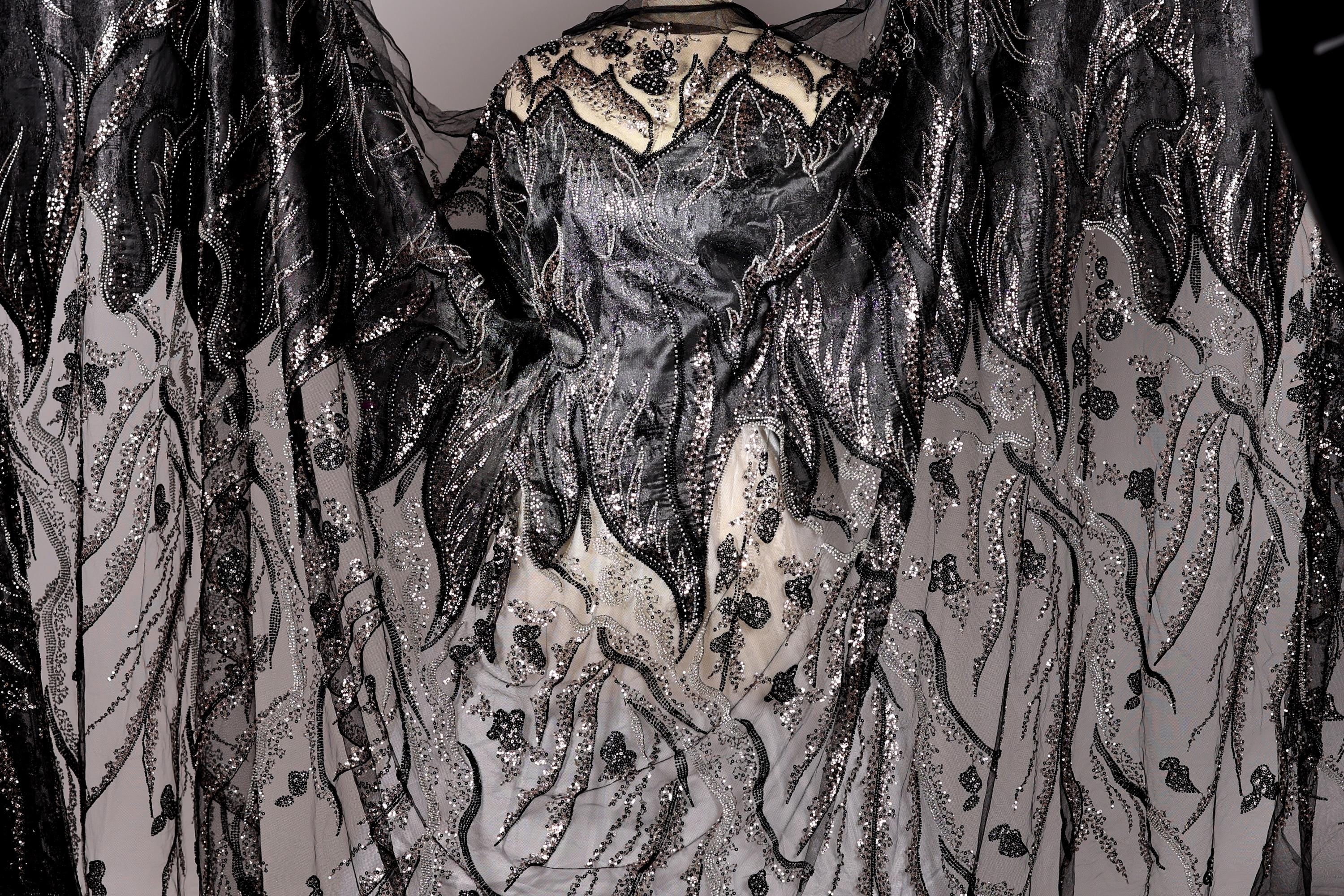 a black and white dress with intricate, detailed embroidery and sequinwork. The dress appears to be a formal or evening gown, with a flowing, draped silhouette. The design is visually striking and eye-catching, with the contrasting black and white colors creating a dramatic effect.