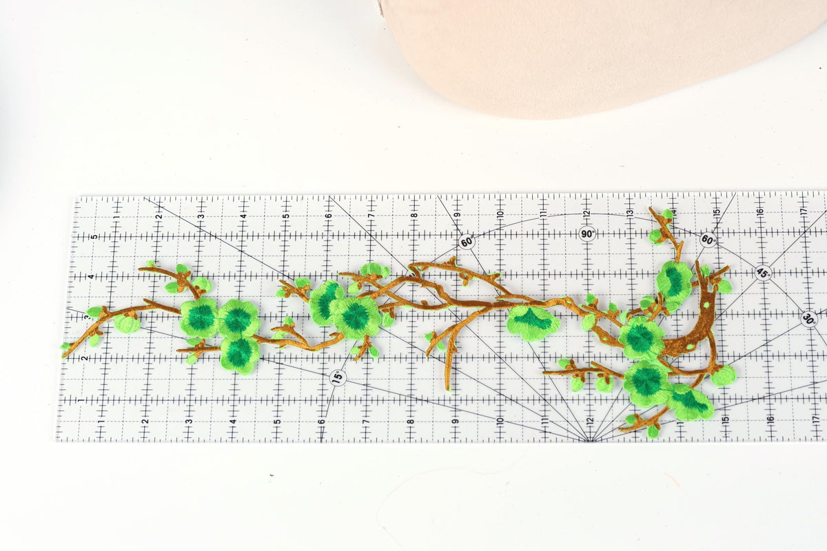 a close-up view of a white ruler with green floral embroidery designs on it.