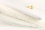 a white fabric, possibly a wedding dress, with a small yellow flower resting on top of it.