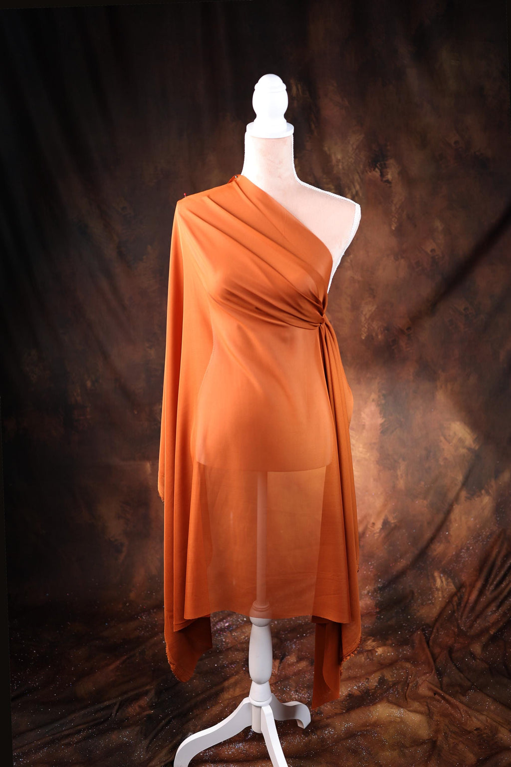 a mannequin wearing an orange draped dress