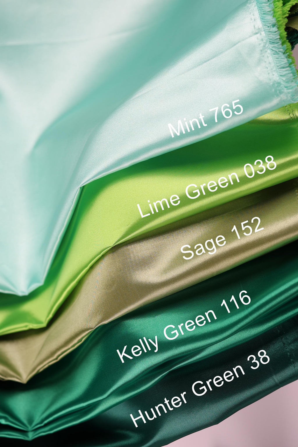 A close-up image of a stack of fabric swatches in various colors, including mint, lime green, sage, Kelly green, and hunter green.