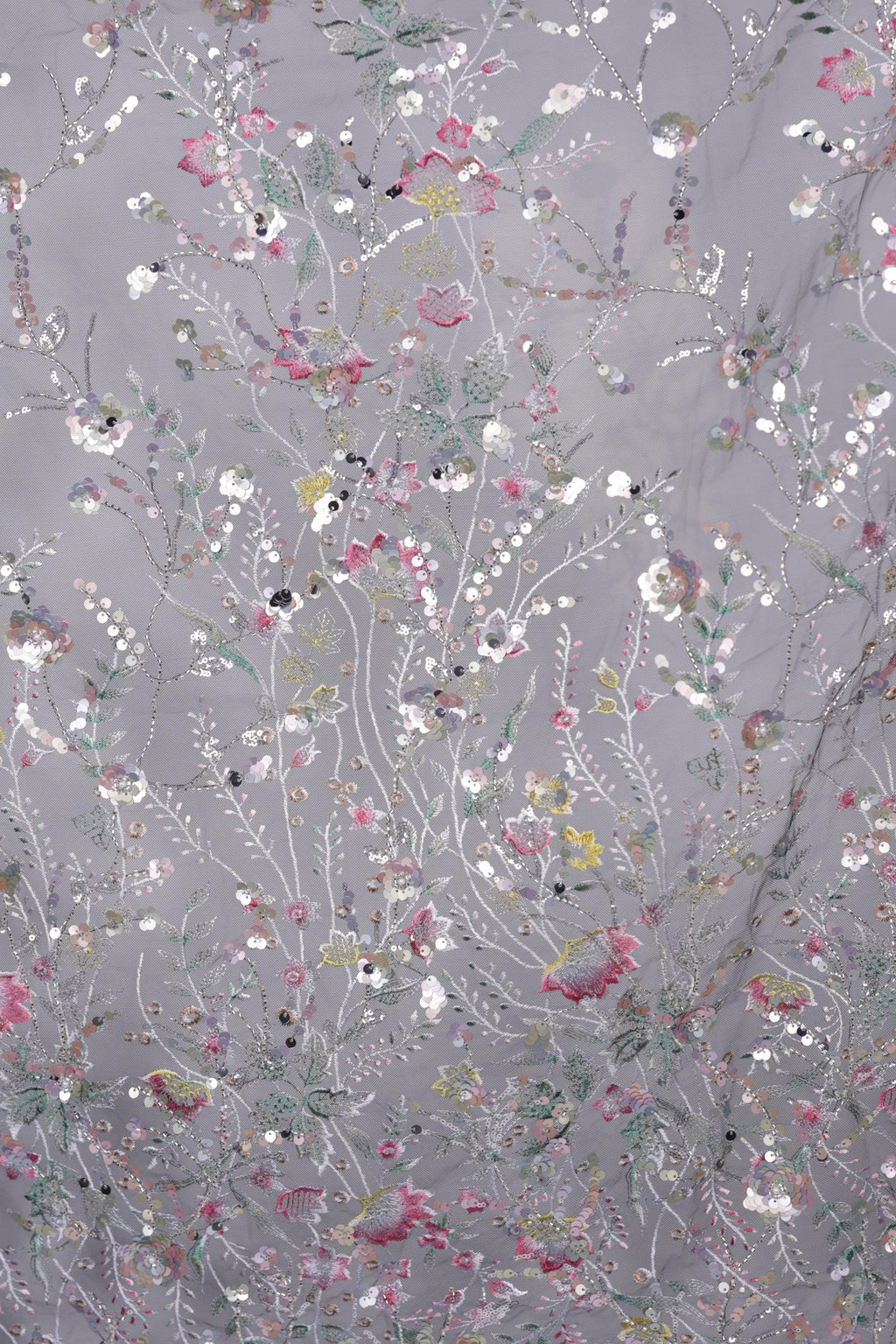 The image is a close-up of a fabric with a floral pattern, featuring a variety of colorful flowers and leaves in shades of pink, white, and green.