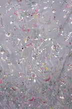 The image is a close-up of a fabric with a floral pattern, featuring a variety of colorful flowers and leaves in shades of pink, white, and green.