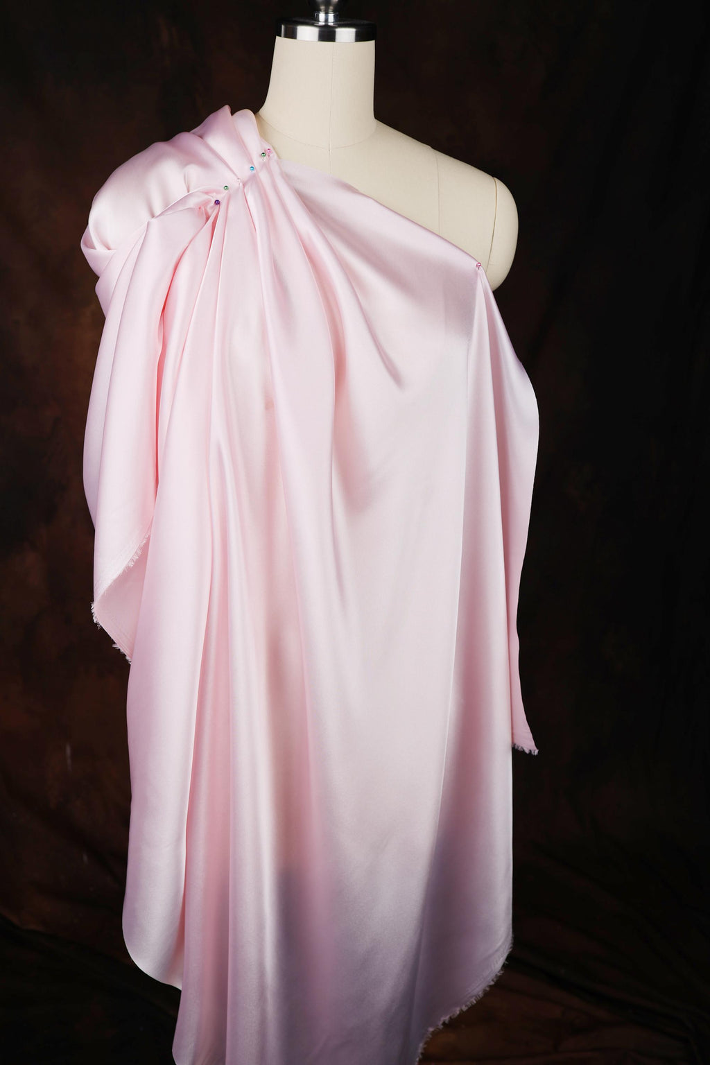 a mannequin wearing a pink draped dress