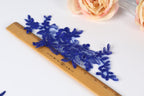 a close-up view of a wooden ruler with blue embroidered flowers placed on it.