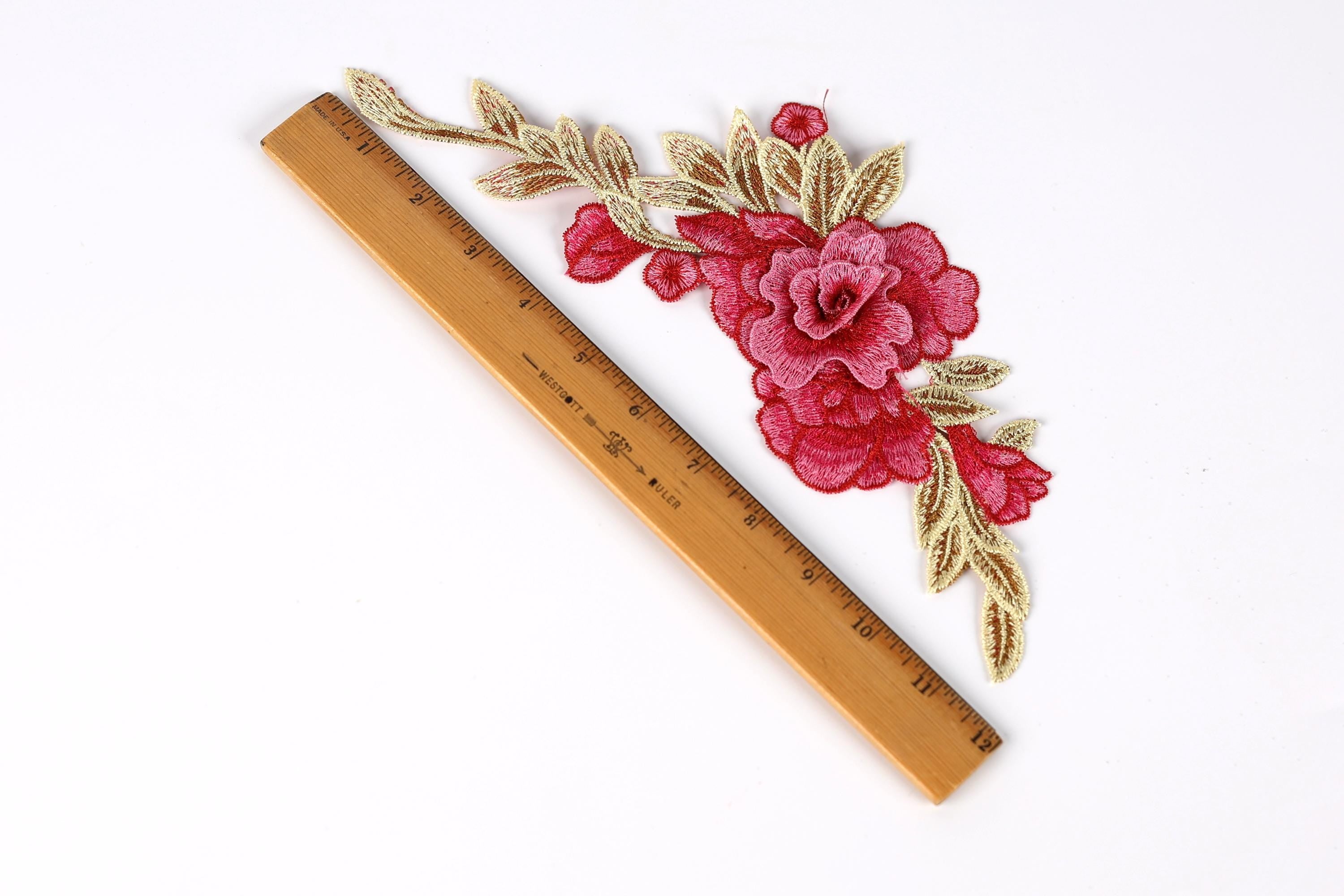 a wooden ruler with a floral embroidered design on it, placed on a white background.