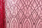 a close-up view of a pink fabric with a repeating pattern of black and pink sequin designs. The pattern is intricate and visually striking, with the sequins adding a touch of sparkle and texture to the fabric.