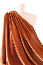 a close-up view of a piece of orange velvet fabric, with its folds and creases visible.