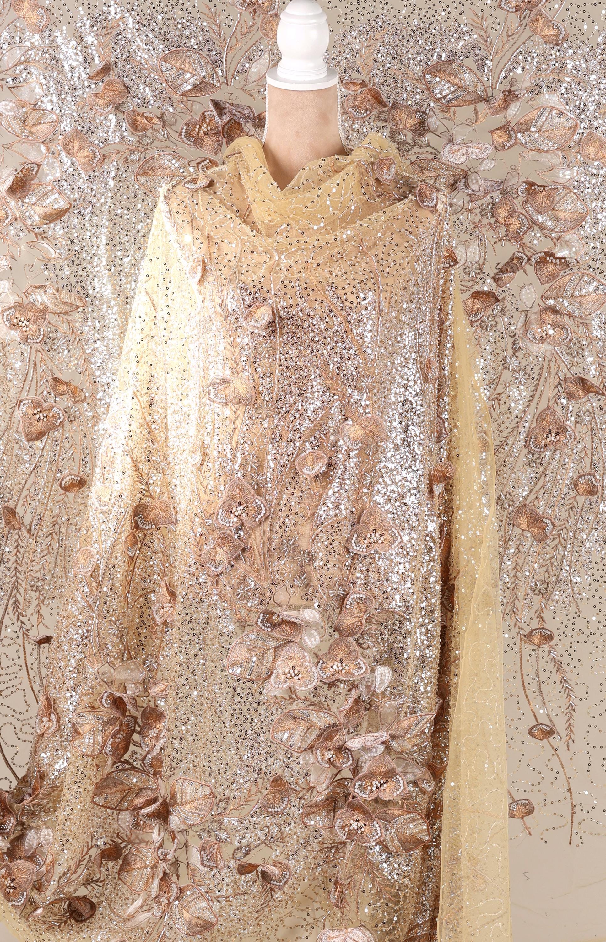 a mannequin wearing a gold and beige sequined dress with a floral pattern.