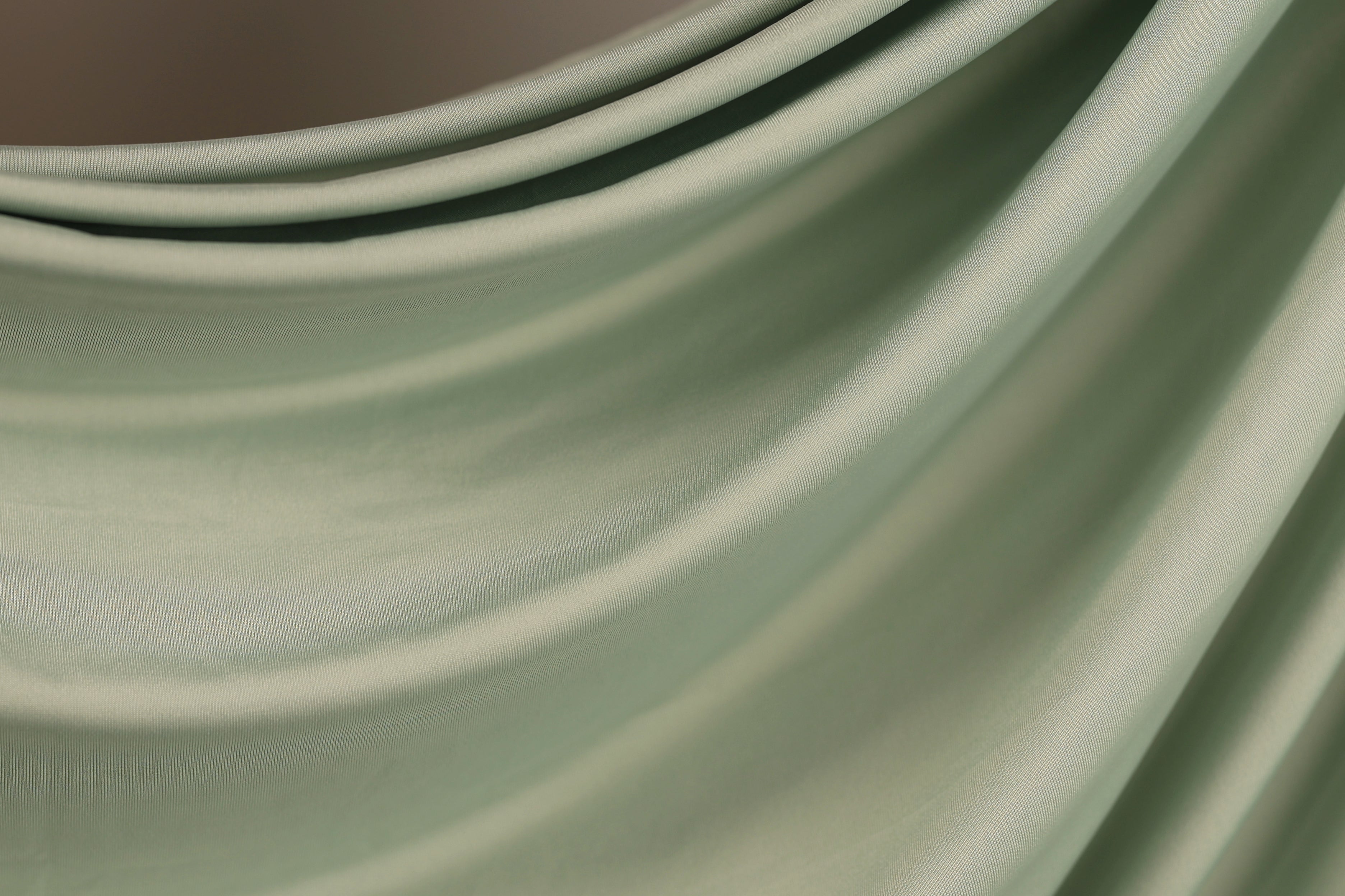 a close-up view of a fabric with a smooth, flowing texture in a light green color.