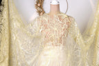 A mannequin wearing a yellow lace dress with a floral pattern.