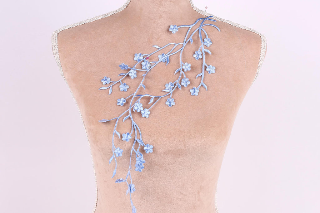 a mannequin torso with a delicate blue floral embroidery on the back.