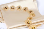 a close-up view of a beige fabric adorned with delicate gold embroidered flowers.