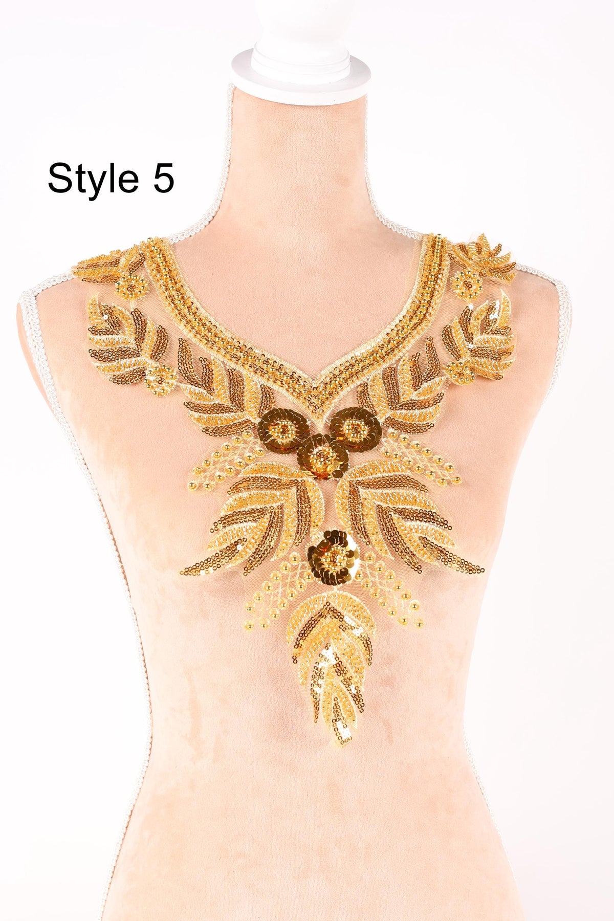 A mannequin wearing a gold and beige sequined neckline with intricate floral and leaf designs.
