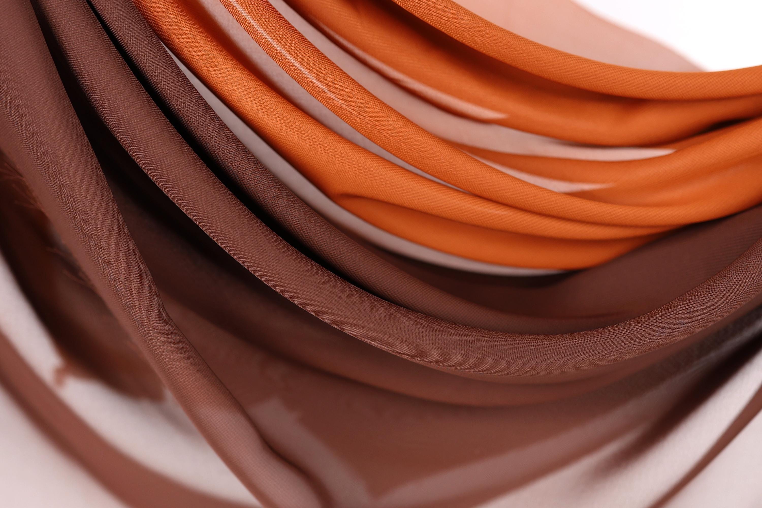 a close-up view of a pile of brown and orange fabric, with the colors blending together to create a visually appealing pattern.
