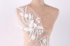 A mannequin torso with a delicate, intricate white lace design on the left side, featuring a floral pattern with white flowers and leaves.