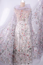 a beautiful, intricately embroidered dress with a floral pattern. The dress is displayed on a mannequin, showcasing its elegant design and the detailed craftsmanship of the embroidery.