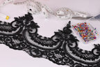 a close-up view of a black lace trim with intricate floral patterns, along with a pair of scissors, a measuring tape, and a container of colorful pins.